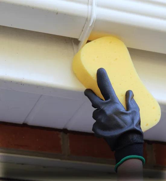 Experienced window cleaners in Reading using a sponge to clean fascia, soffit, and cladding, ensuring a thorough and safe service