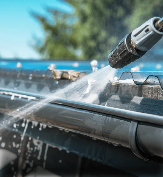 Window cleaners in Reading performing gutter cleaning with high-pressure water, maintaining clear gutters and preventing damage to the home